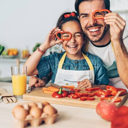 Father and daughter cooking and slicing vegetables.