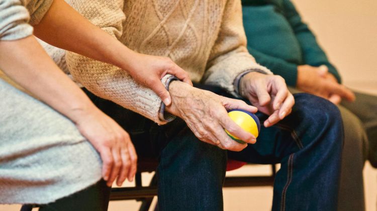 A person holding another's hand, as they clutch a stress ball.