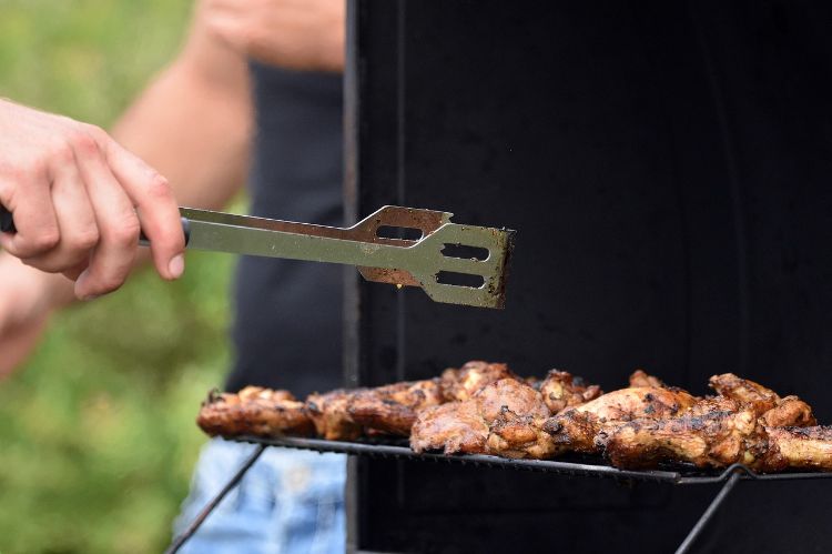 A person grilling meat outside.