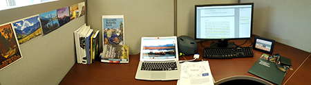 Desk with two computers and books on it