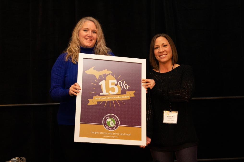 Two women stand with an award