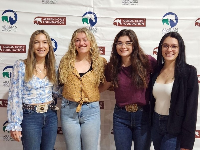 Four youth standing in front of the Arabian Horse Youth Association banner.