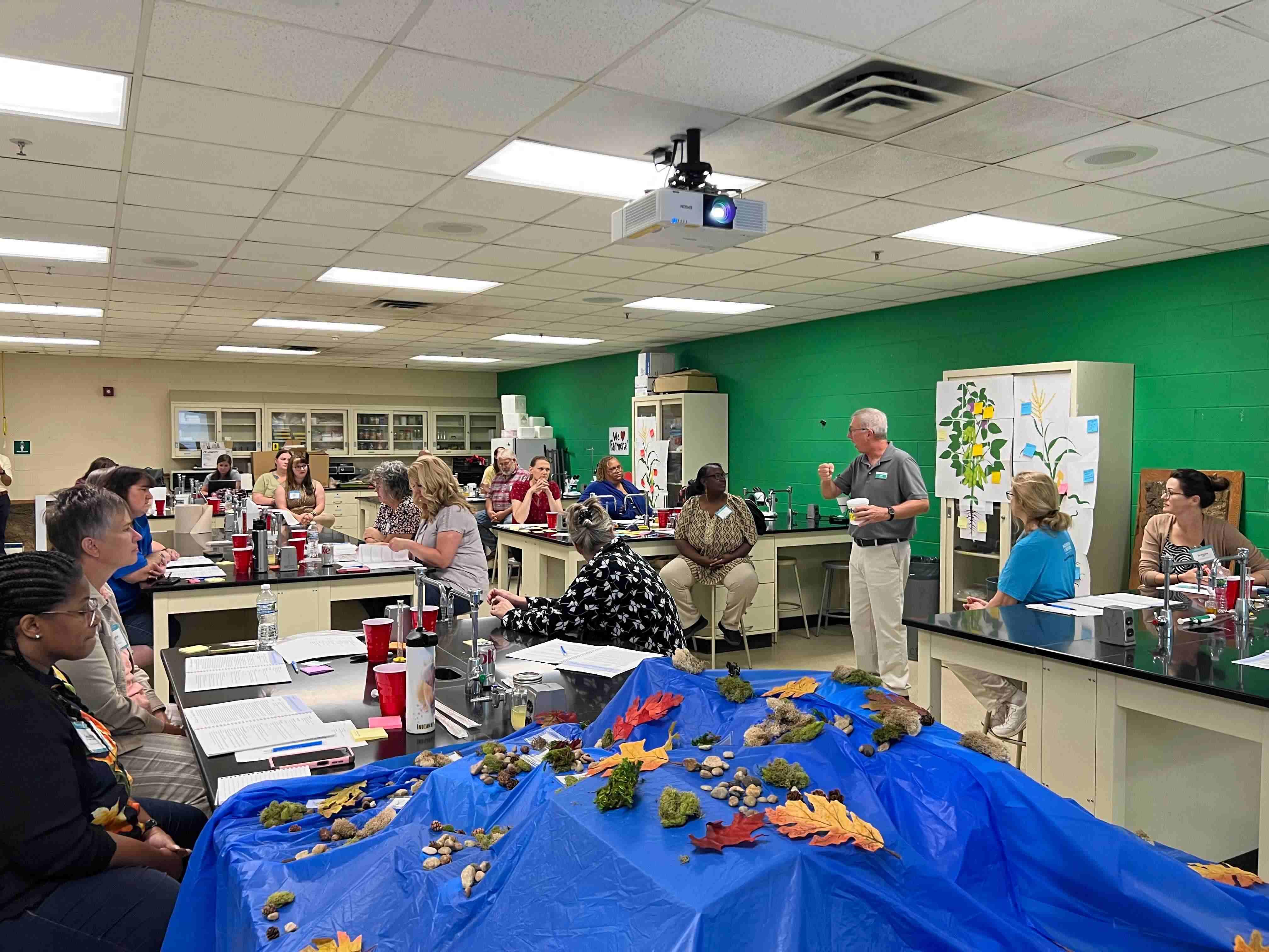 Teachers surround a lab bench cooperating on experiments. 