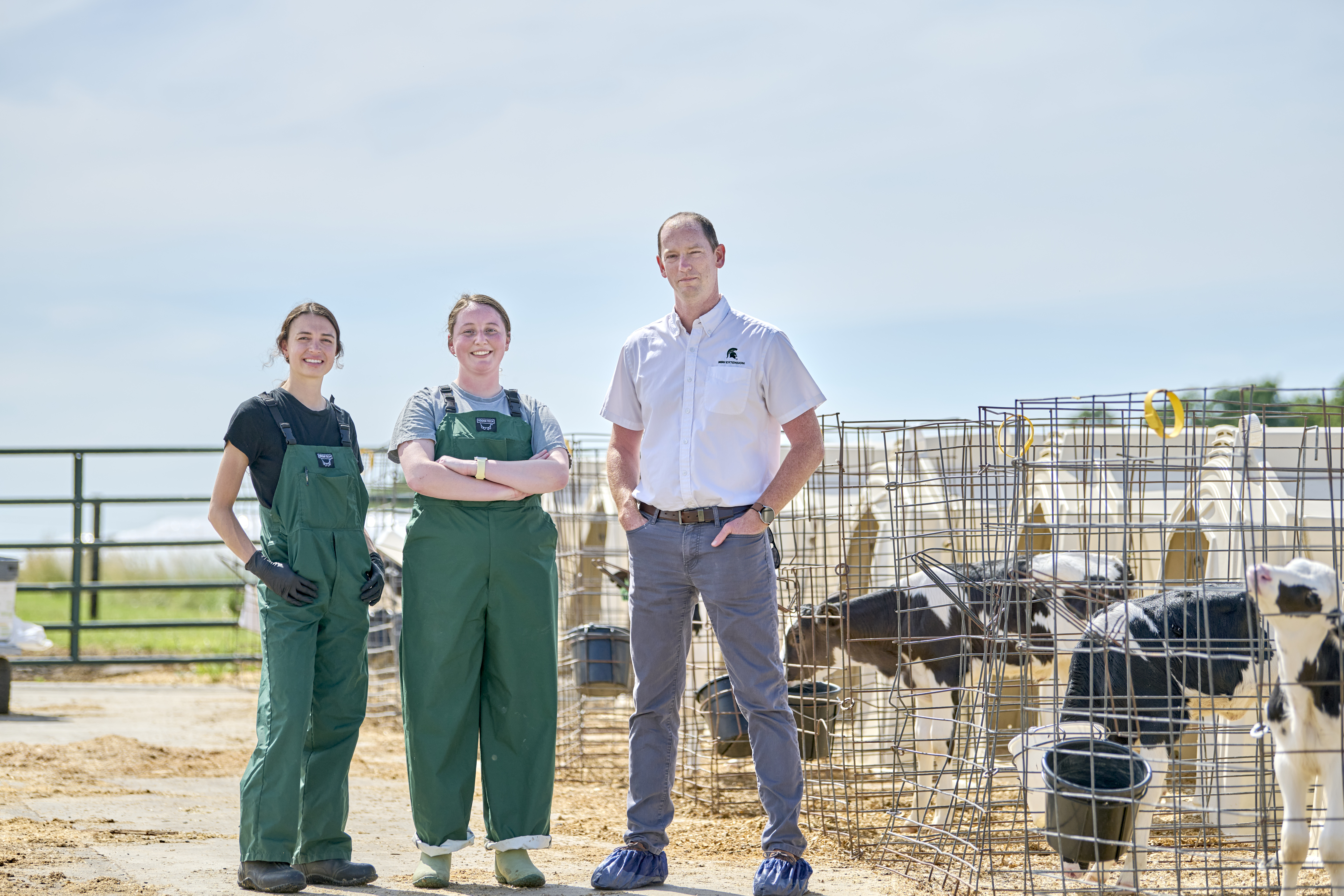 Haylee, Paiton and Barry Bradford stand in a group outside in front of outdoor calf pens