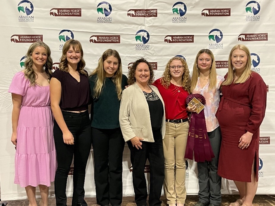 Seven youth and adults standing in front of the Arabian Horse Foundation banner.