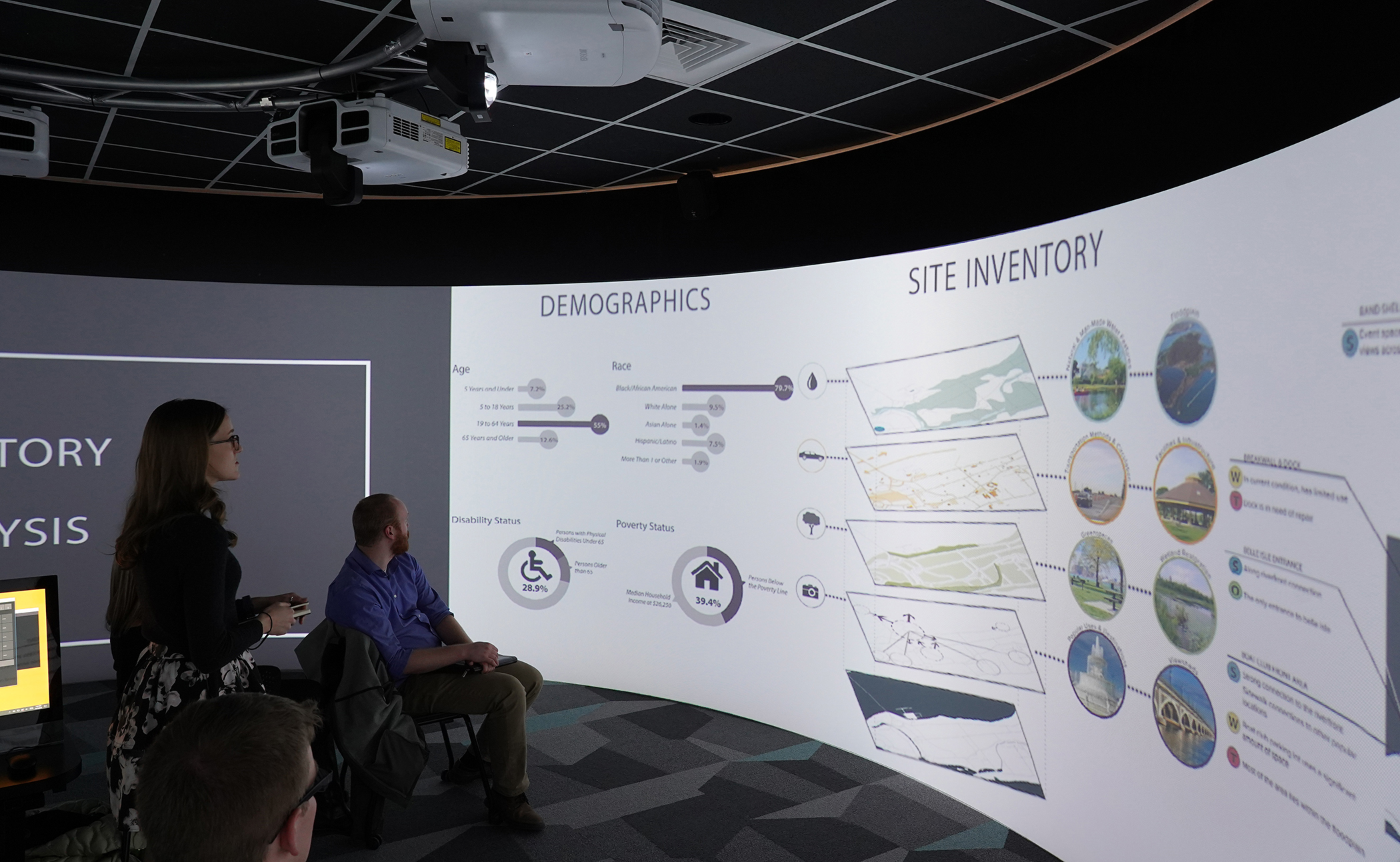 Landscape architecture student presenting their project during the LA Senior Show. Using VR technology, the student's project is presented on a screen that runs around the perimiter of the round room.